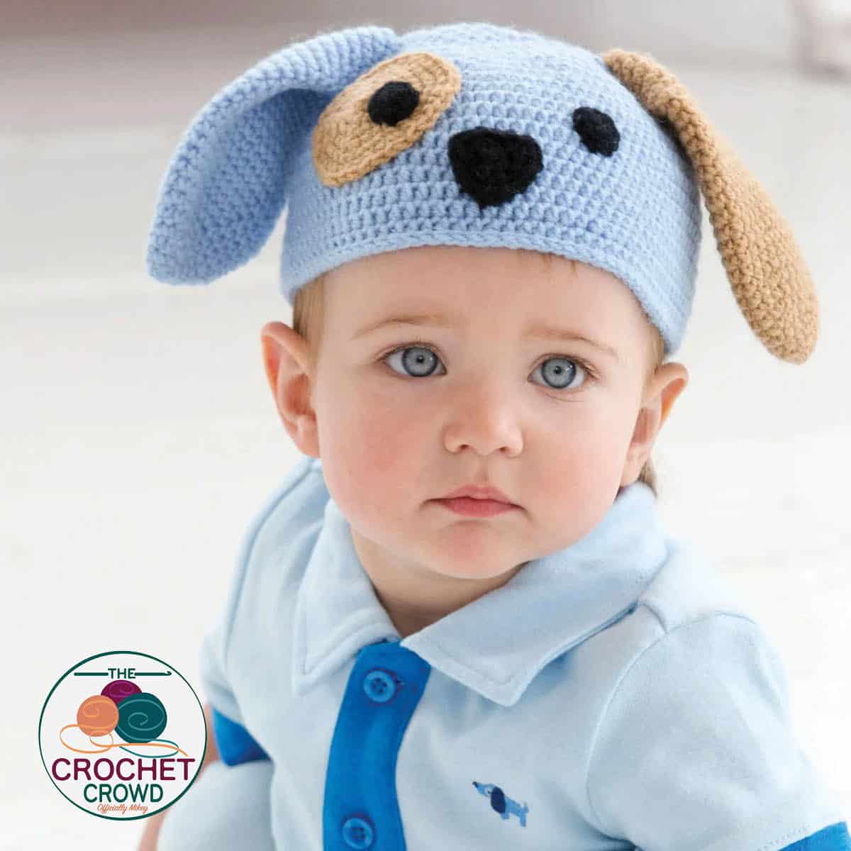 A baby wearing a blue dog hat.