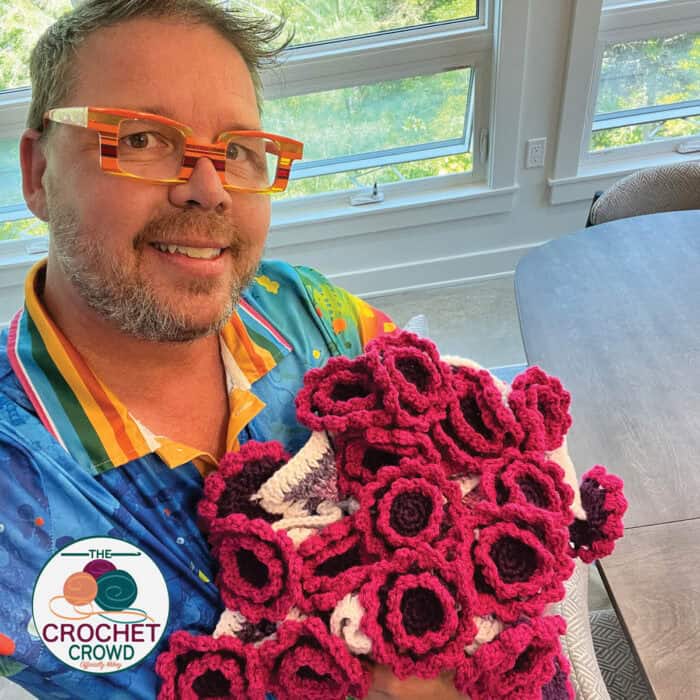 A man holding a bunch of crocheted flowers.
